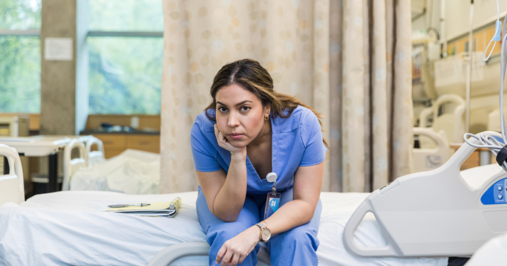 A nurse looking upset on a hospital bed because she has received an accusation from the BRN. 