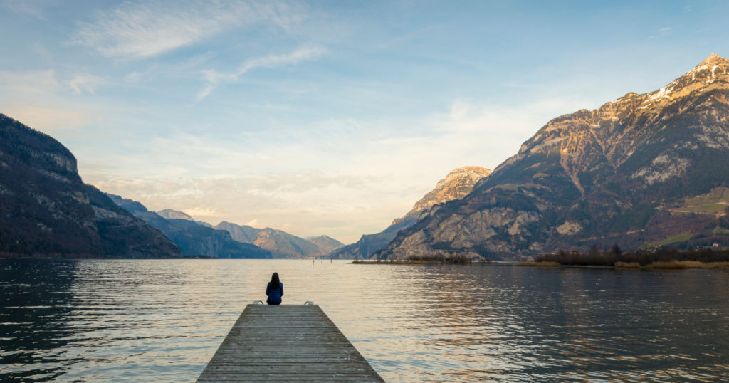 Woman sitting on a dock overlooking the lake.